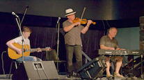 Kyle MacNeil on fiddle, Sheumas MacNeil on keyboard, and Malcolm MacNeil on guitar