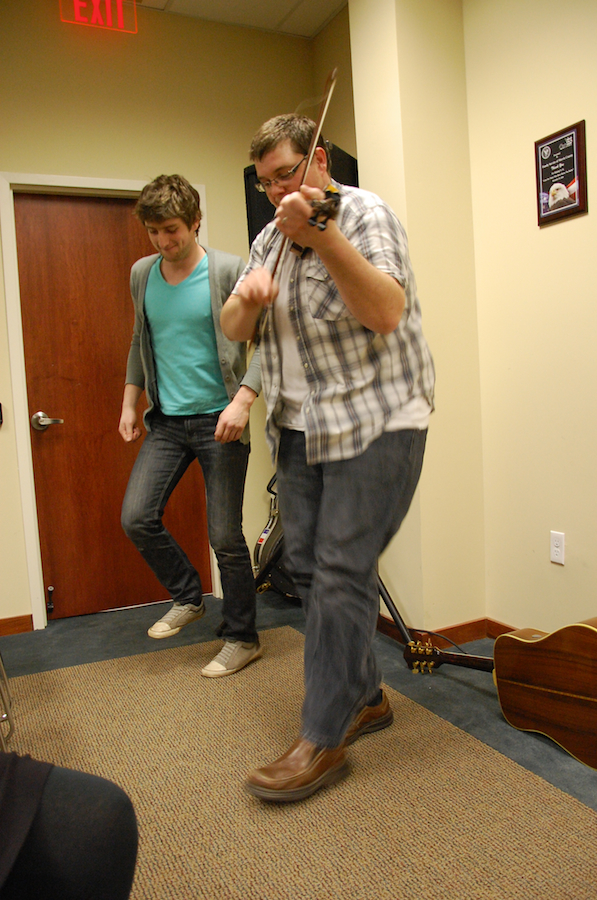 Photo of Koady Chaisson step-dancing while J. J. plays the fiddle and step-dances