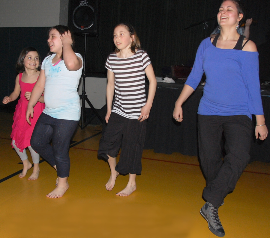 Photo of Morgan McCasland, Brittany ?, Molly McCasland, and Zoë Darrow step-dance to the music of J. J. and Koady Chaisson