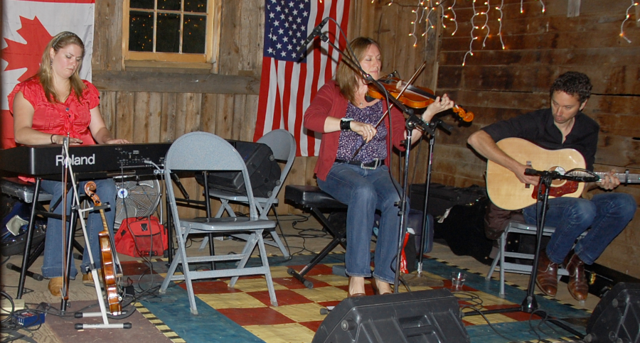 Photo of Wendy MacIsaac on fiddle accompanied by Andrea Beaton on keyboards and Seph Peters on guitar
