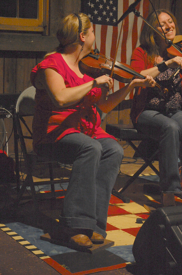 Photo of Andrea Beaton and Wendy MacIsaac on fiddles share a laugh
