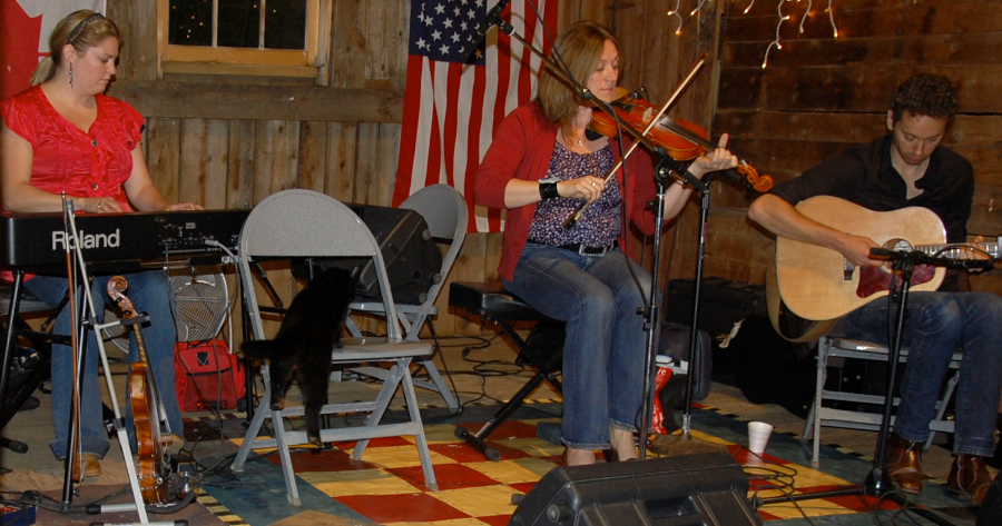 Photo of Wendy MacIsaac on fiddle accompanied by Andrea Beaton on keyboards and Seph Peters on guitar as the Black Cat goes for it