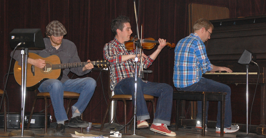 Photo of Colin Grant on fiddle accompanied by Adam Young on piano and Jason MacDonald on guitar,