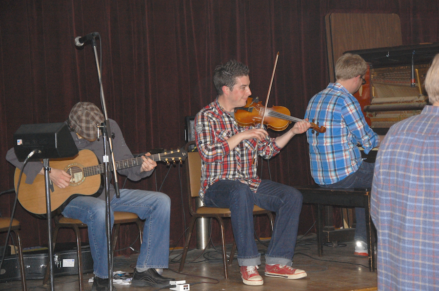 Photo of Colin Grant on fiddle accompanied by Adam Young on piano and Jason MacDonald on guitar,